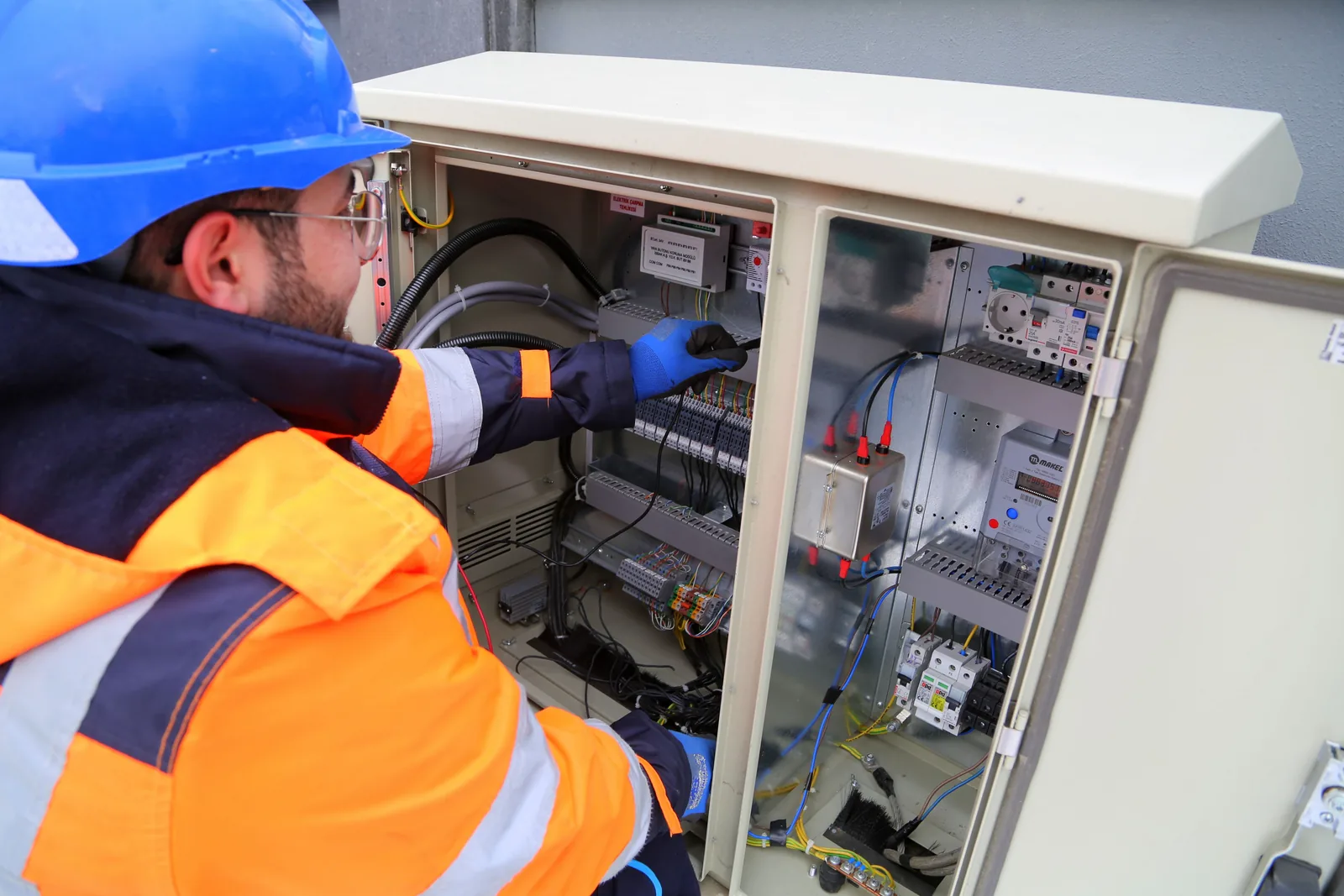 An electrician working in an outdoor service cabinet, for maintenance plans in Cincinnati
